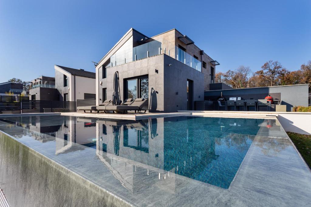 a swimming pool in front of a house at Villa Porta Verde IV - Infinity pool BBQ Luxury in Balatonalmádi