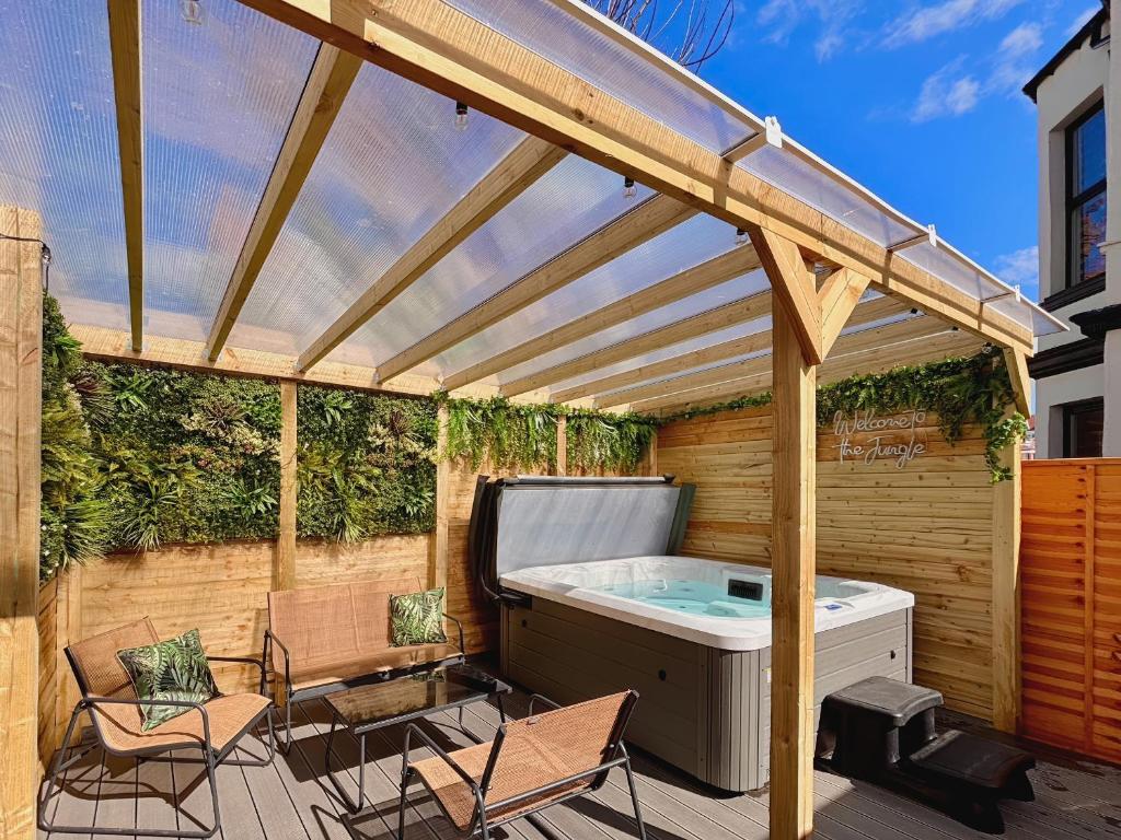 a hot tub on a deck with a pergola at Clarence House in Llandudno