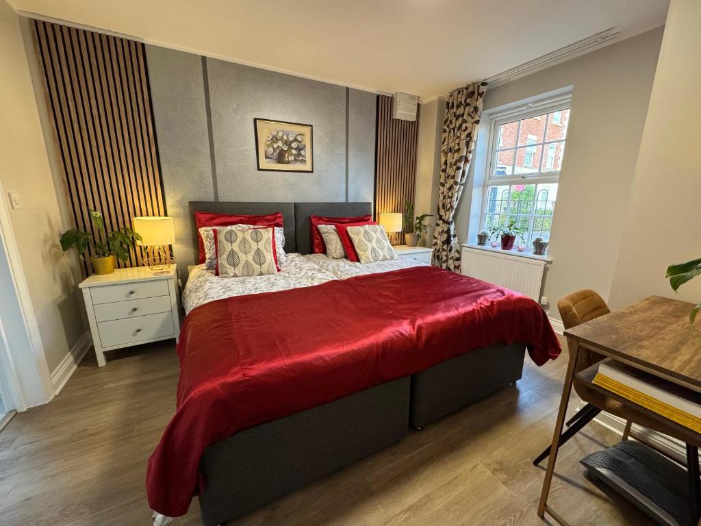 a bedroom with a large bed with a red blanket at Chrysanthemum Drive stays in Shinfield