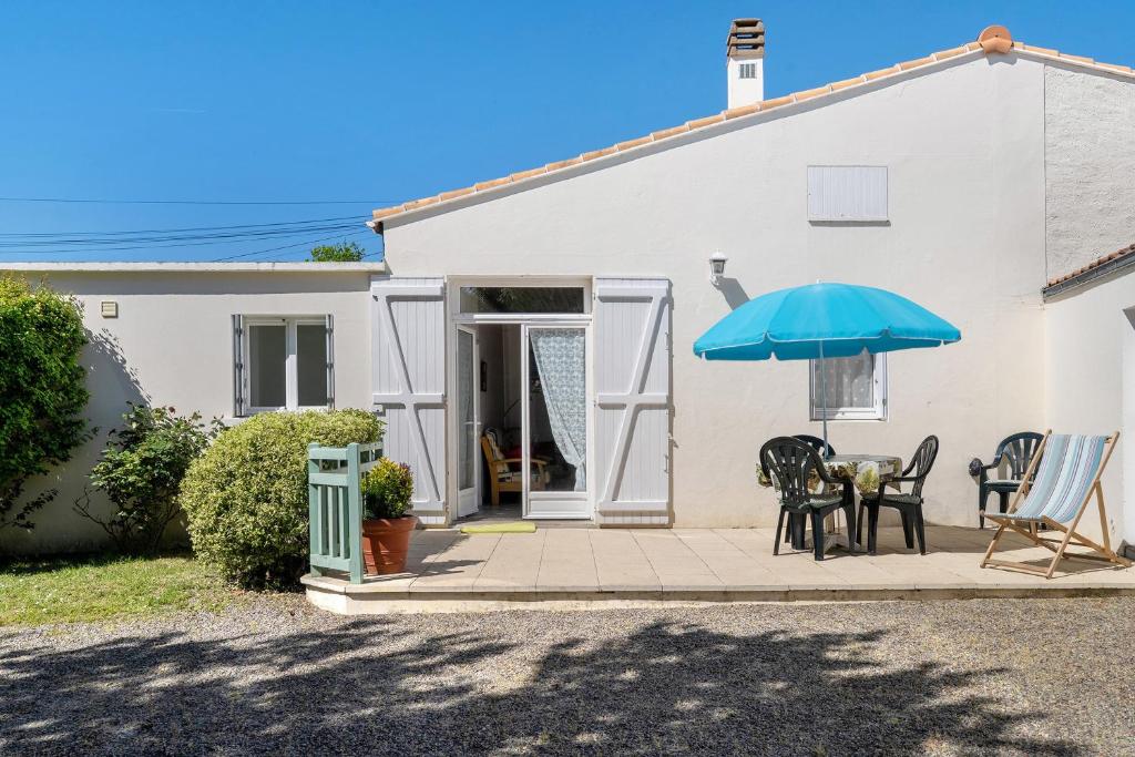 a white house with a table and an umbrella at Maison Pêcheur, jardin et plage -1 in Pornic