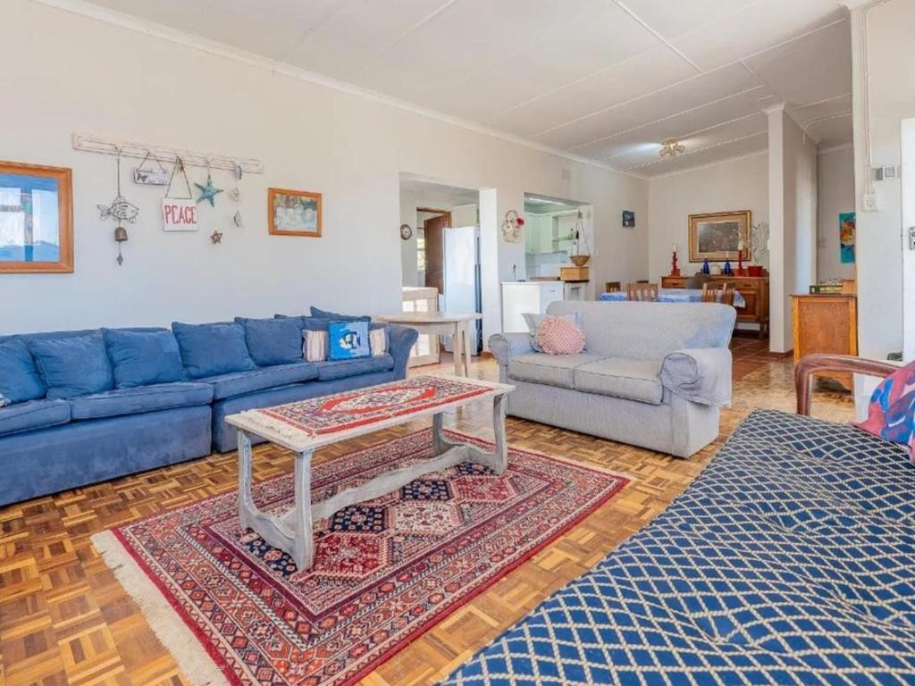 a living room with blue couches and a table at Kusweg Oos 1 in Struisbaai