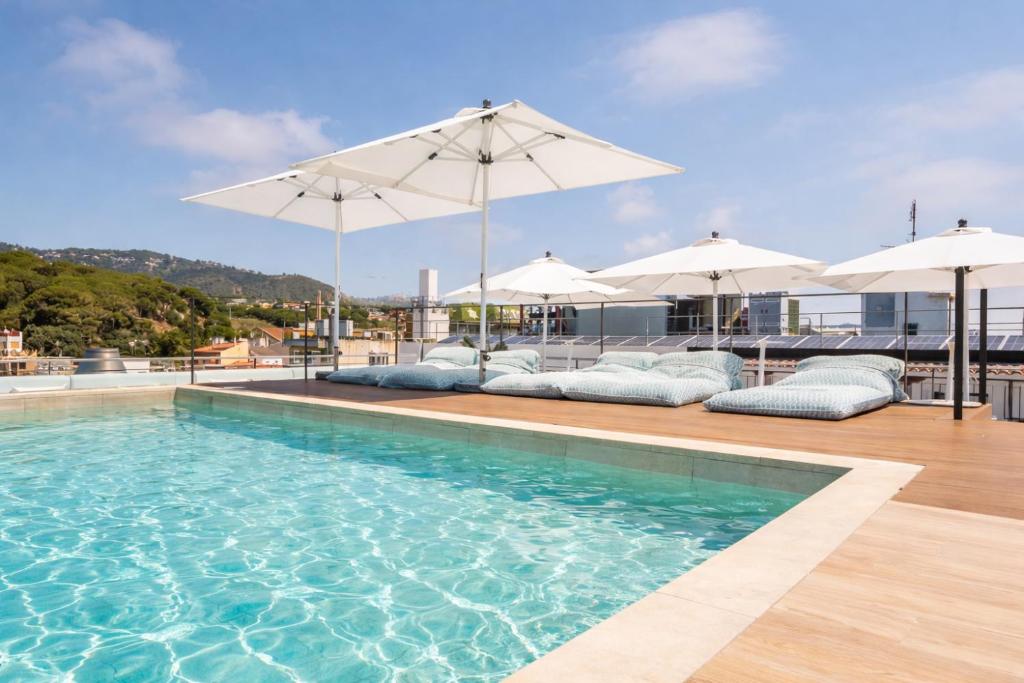 a swimming pool with chairs and umbrellas on a building at Neptuno Hotel & SPA 4 Sup in Calella