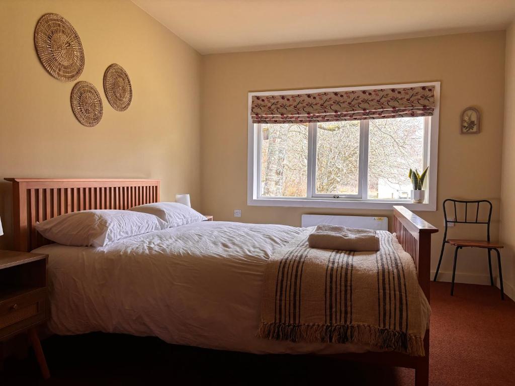 a bedroom with a bed and a window and a chair at Kindrogan House in Straloch