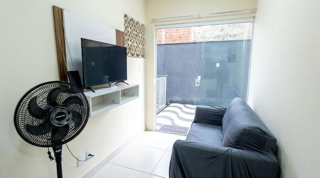 a living room with a couch and a fan at Studio Funcional c Wifi perto do Centro Itabuna in Itabuna