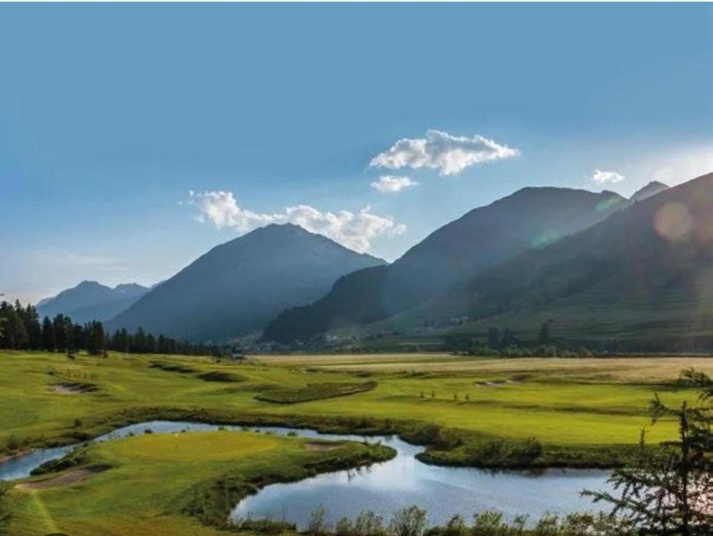 a view of a golf course with mountains in the background at Kleines aber feines Studio in Zuoz