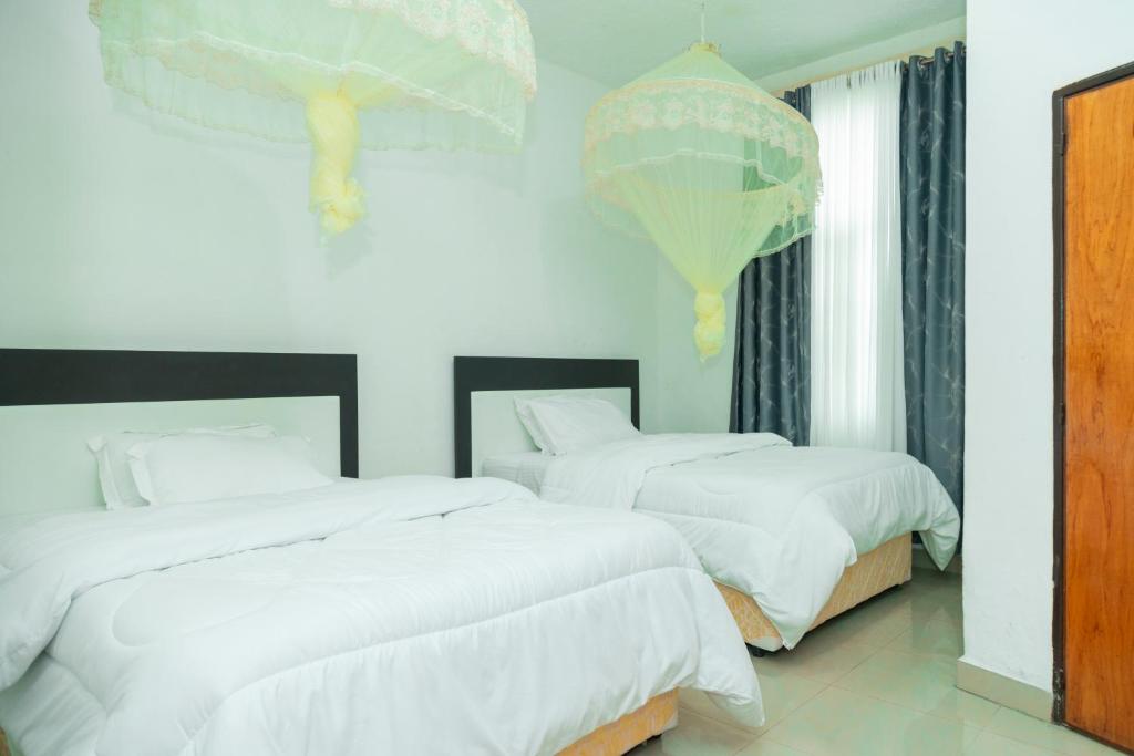 a bedroom with two beds with white sheets and balloons at Kibeho Pilgrimage Center in Giseke