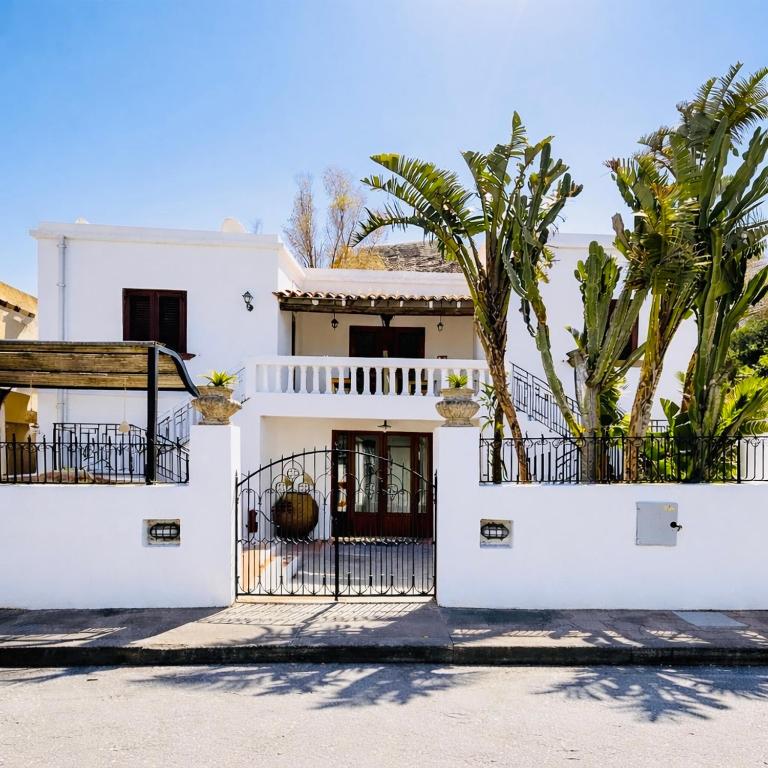 a white house with a gate and palm trees at La Casa al Mare Vulcano in Vulcano