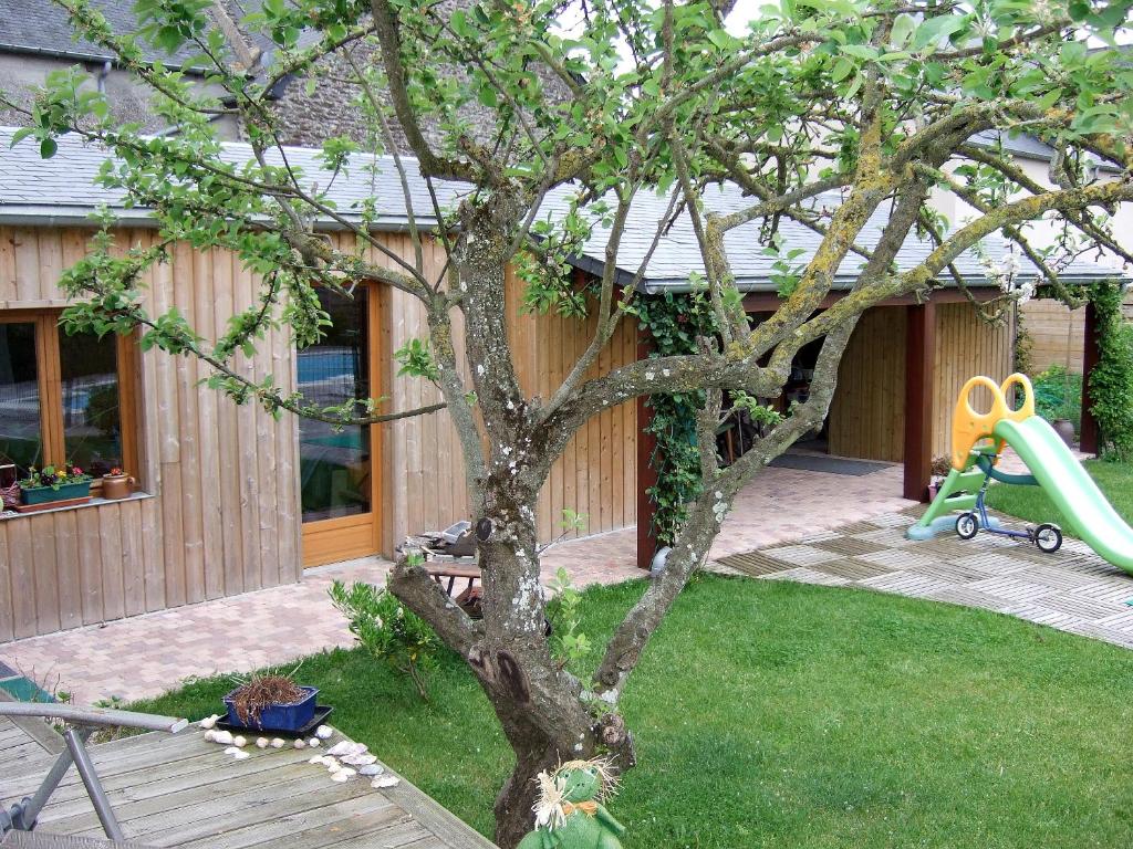 a tree in front of a house with a playground at La Grande Mare in Saint-Benoît-des-Ondes