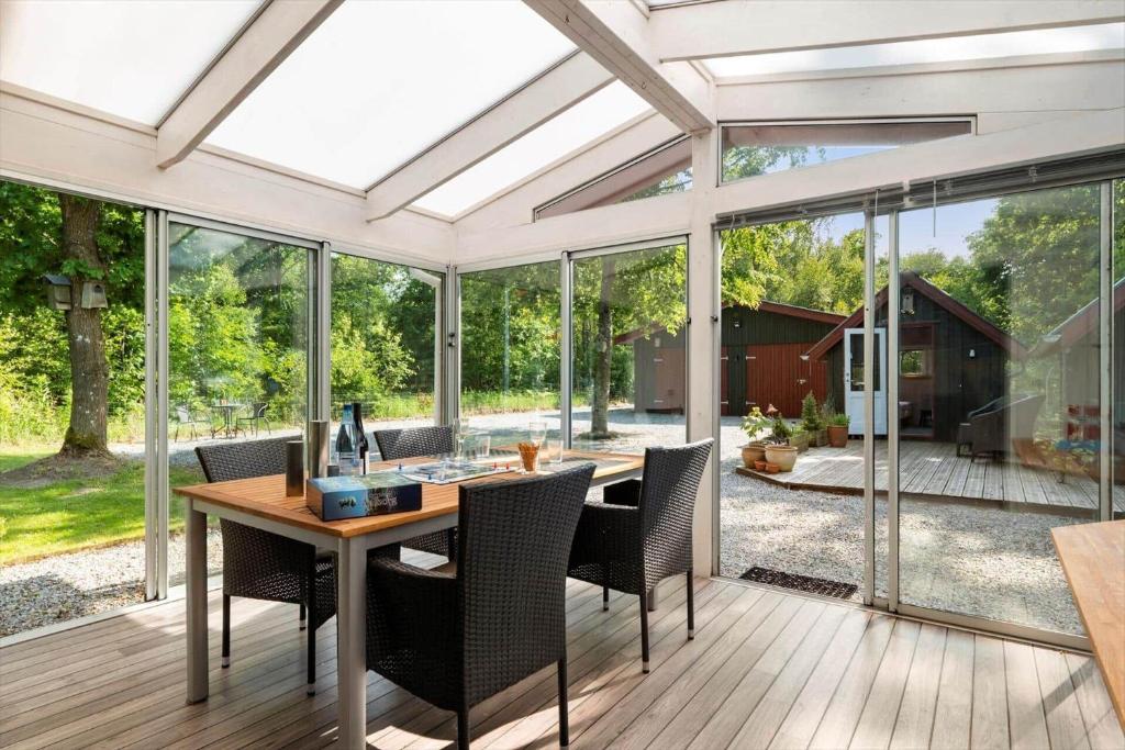 a conservatory with a table and chairs and windows at HA378-Saeby-Krebsevej-2 in Sæby
