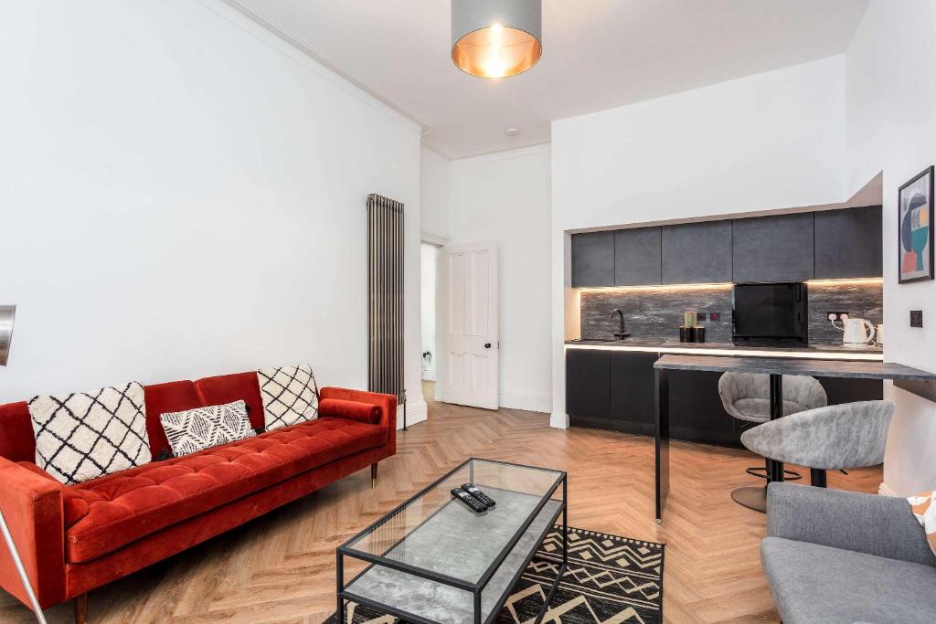 a living room with a red couch and a kitchen at The Fairlie Suite No1 in Prestwick