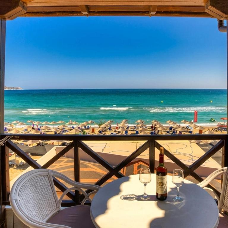 a table with wine glasses and a view of the beach at Troulis Seaside in Amoudara Herakliou