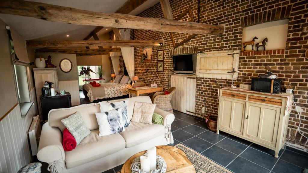 a living room with a couch and a brick wall at B&B Hoeve Westdijk in Oostkamp