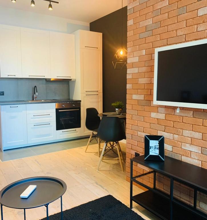 a kitchen with a tv and a brick wall at Tarnowskiego City Apartaments in Kutno