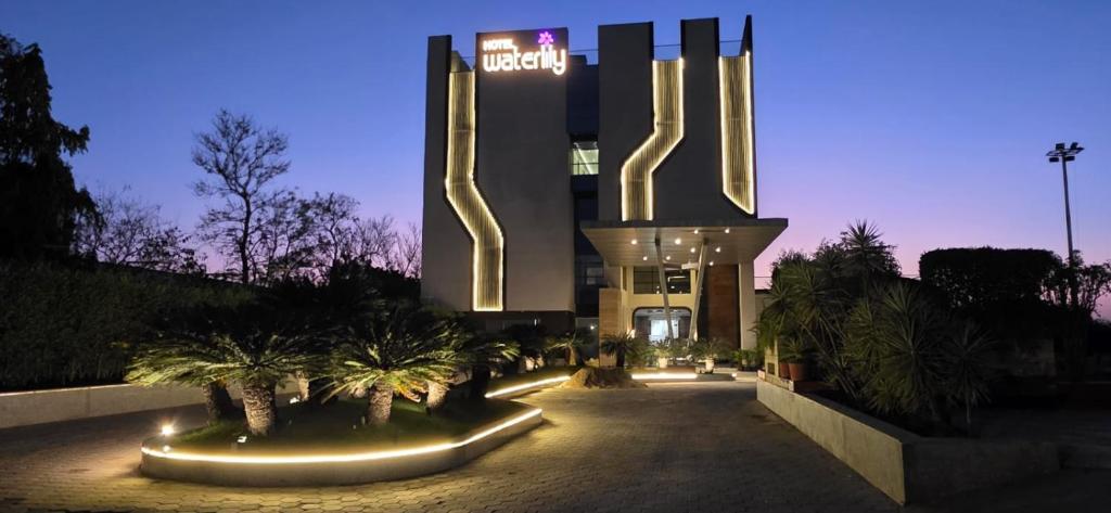 a hotel with a building with palm trees in front of it at Hotel Waterlily in Indore