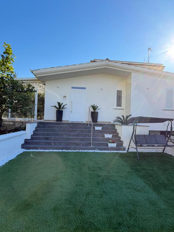 a white house with stairs and a lawn at Villa Amelia in Capaci