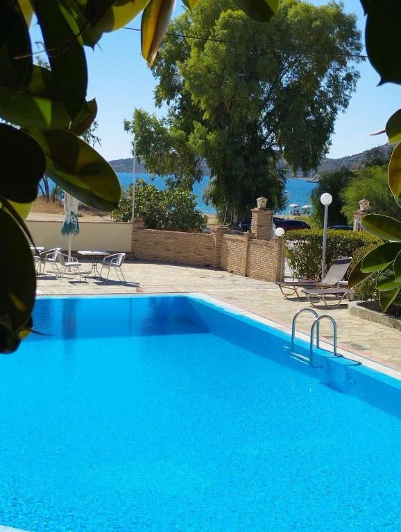 a blue swimming pool with a view of the water at Zakros Beach hotel in Tolo