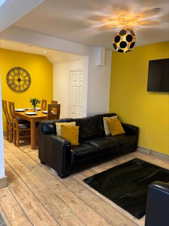 a black leather couch in a living room with a soccer ball on the wall at Evas place in Llandudno