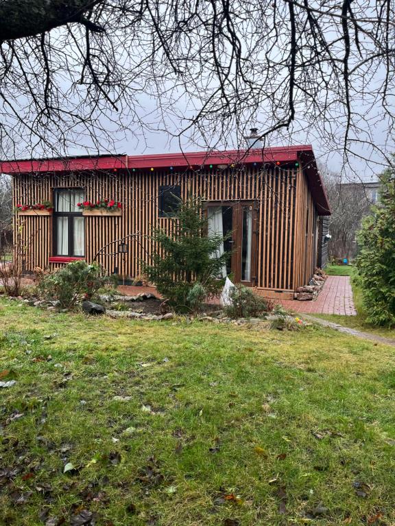 a small house with a red roof on a yard at Atpūtas vieta ar pirti, with wi-fi, self check in and private parking in Ventspils