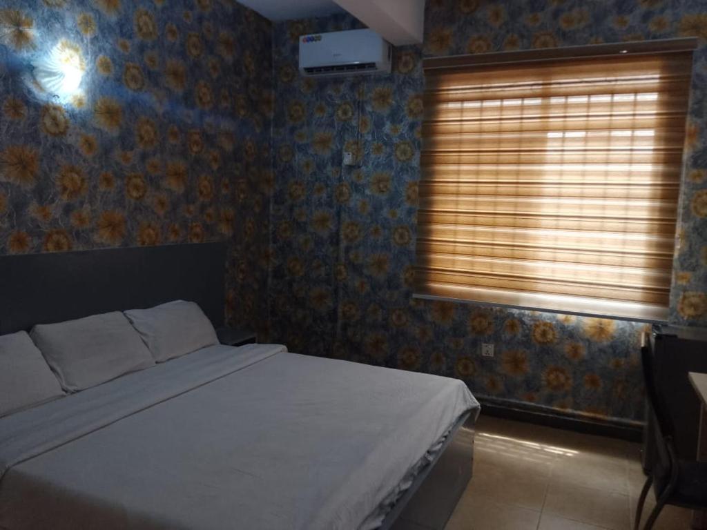 a bedroom with a bed and a window with blinds at Transit Care Hotel in Port Harcourt