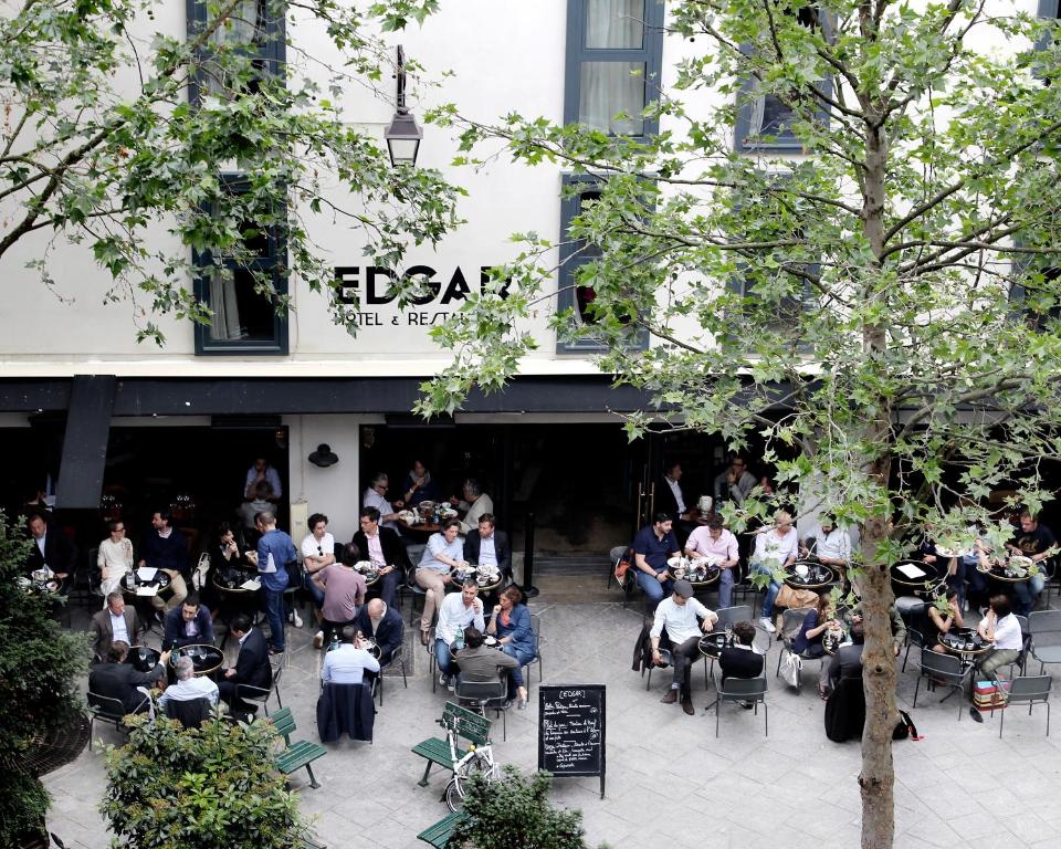 une foule de personnes assises devant un bâtiment dans l'établissement Hôtel Edgar & Achille, à Paris