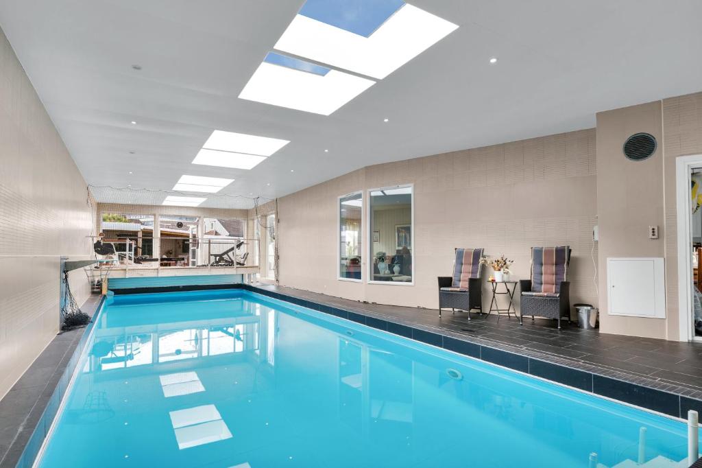 a large swimming pool with blue water in a building at Villa Stavanger 5 bedrooms 5 bathrooms and large swimming pool in Stavanger