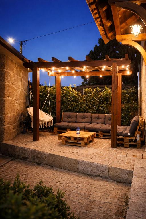 a patio with a couch under a pergola at night at Refugio dos Coviais in Guarda
