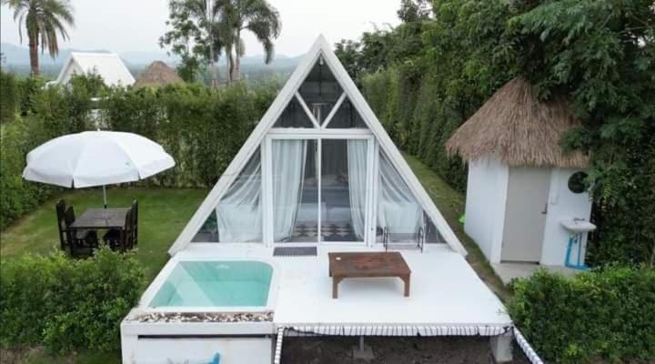 a small tent with a pool and a table and an umbrella at Phunapat camping in Cha Am