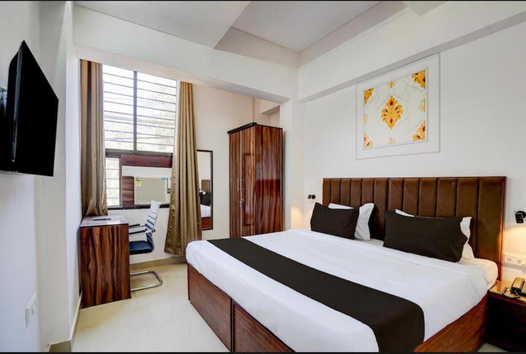 a bedroom with a bed and a desk and a television at Hotel Vijai Square in Prayagraj