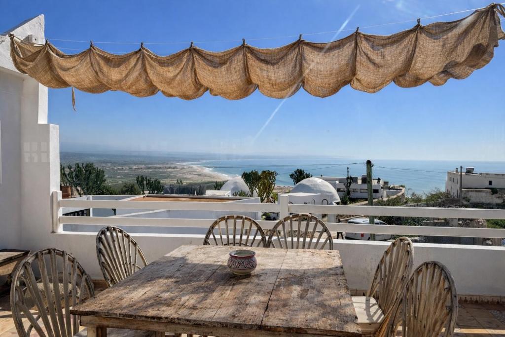 a wooden table and chairs on a balcony with a view at Pistach Océan Maison 4 chambres vue Océan in Wassane