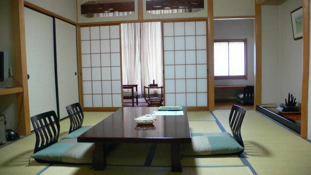 comedor con mesa de madera y sillas en Oyado Sansui en Achi