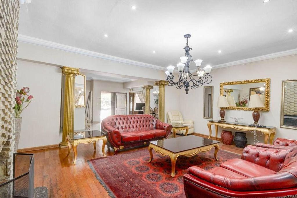 a living room with red furniture and a chandelier at The Adress beautiful in Midrand