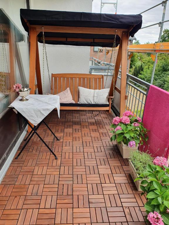 a porch with a swing on a balcony with flowers at Zimmer an der Wedel in Burgwedel