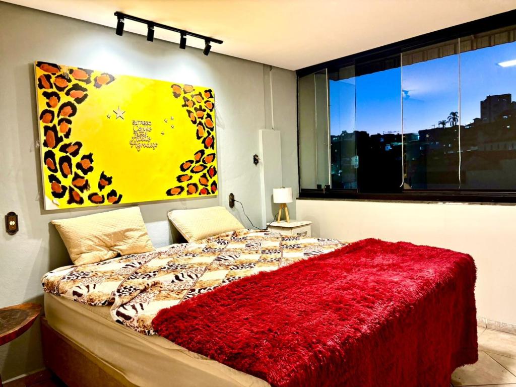 a bedroom with a bed with a red blanket at Solar Boutique Residence in Pouso Alegre