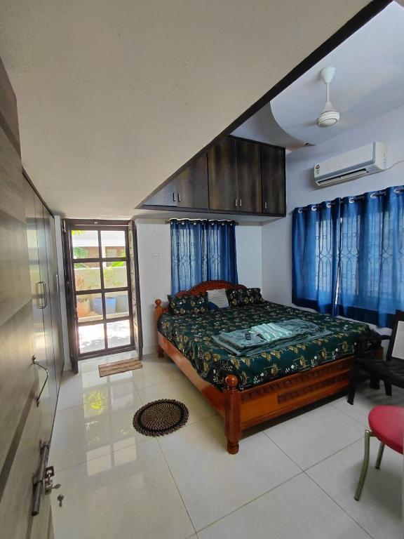 a bedroom with a bed with blue curtains and a window at Elite stay villa in Vākalapūdi