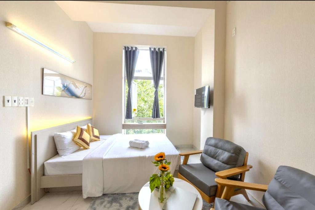 a bedroom with a bed and a chair and a window at G8 Le Van Sy Hotel Saigon in Ho Chi Minh City
