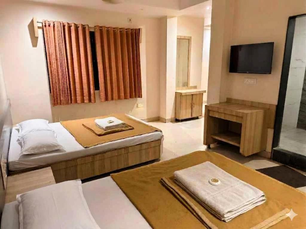 a hotel room with a bed and a television at SD Blueberry Hotel in Shirdi
