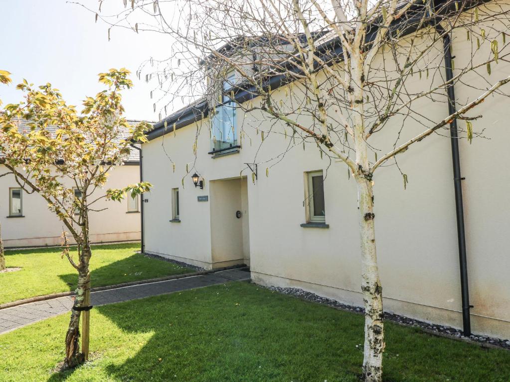a building with two trees in front of it at Oak Tree Cottage - Gower in Swansea