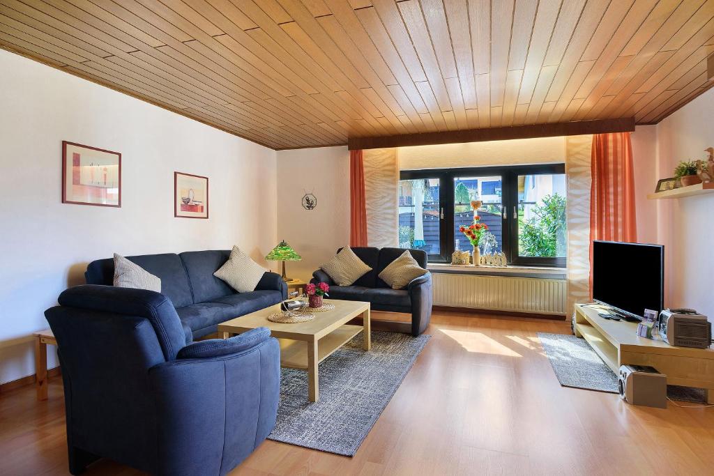 a living room with a blue couch and a table at Eifelferienhaus Thome Lissendorf in Lissendorf