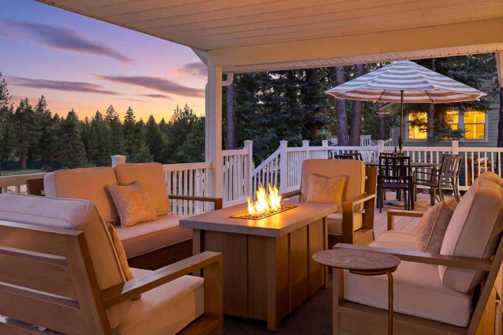 a porch with chairs and a table and an umbrella at The Fairway To Heaven in Rathdrum