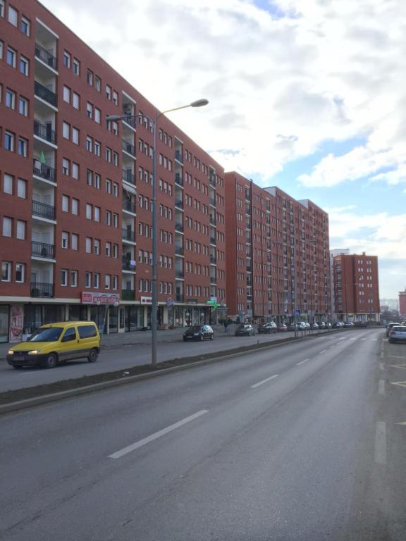 una calle urbana vacía con edificios altos y un coche amarillo en Apartment Royal, en Pristina