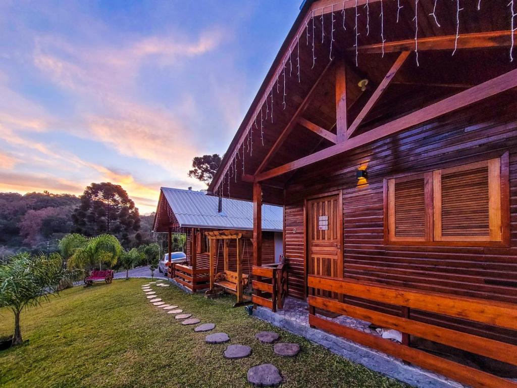 a log cabin with a pathway next to a building at Cabanas Sitio Amigos in Bento Gonçalves
