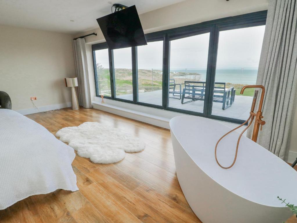 a bedroom with a tub and a view of the ocean at Pengarnedd in Amlwch