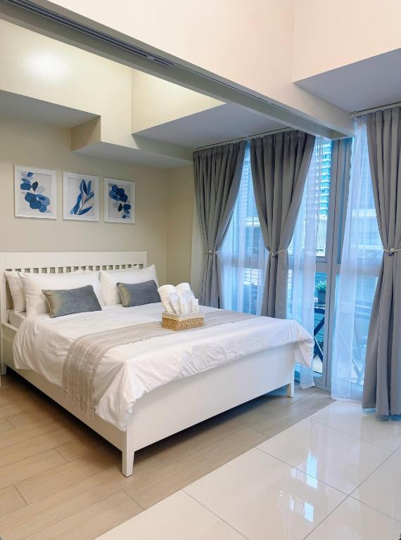 a bedroom with a large white bed and large windows at Parksuites Tower 2 in Manila