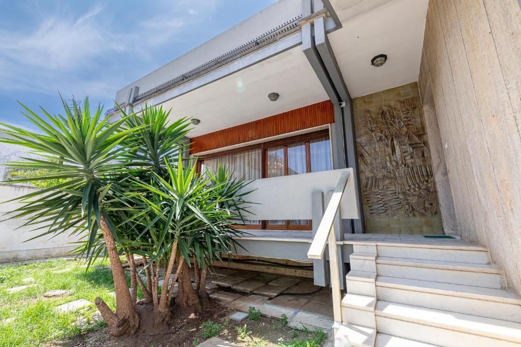 a house with stairs and palm trees in front of it at Villa dei Domenicani in Copertino