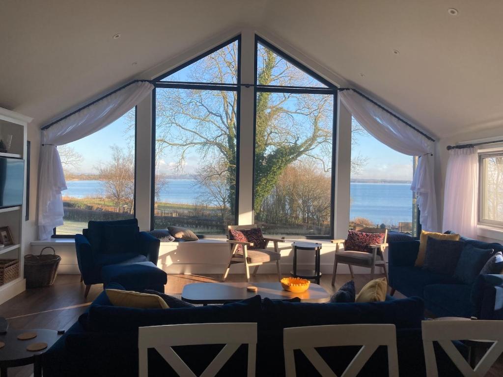 a living room with blue couches and large windows at Lough View Lodge in Ballyronan