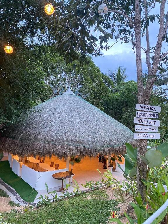 a large hut with a thatched roof and a sign at Coron Cozy Nature Hut in Coron