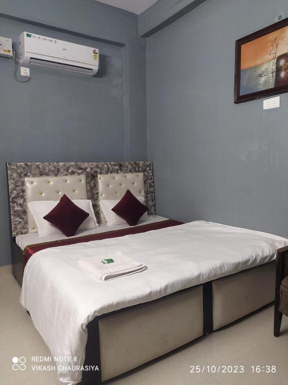a bedroom with a bed with white sheets and pillows at Hotel Radhika Palace in Mirzāpur