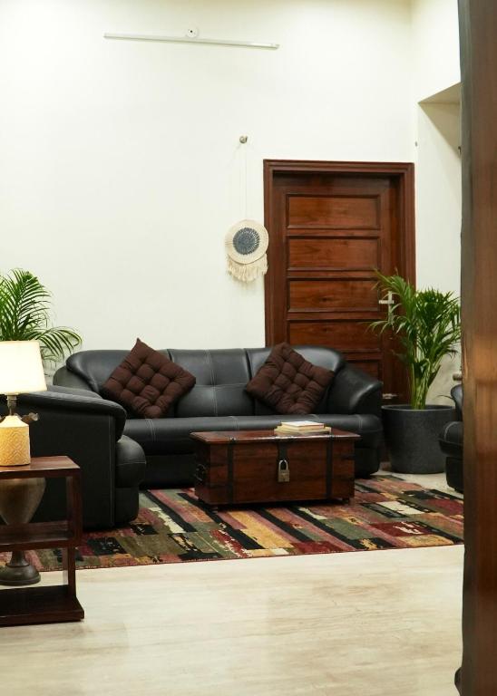 a living room with a black couch and a coffee table at Autumn House in Jaipur