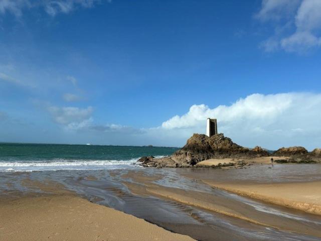 a lighthouse on an island in the ocean on a beach at Les Mûres in Saint-Lunaire