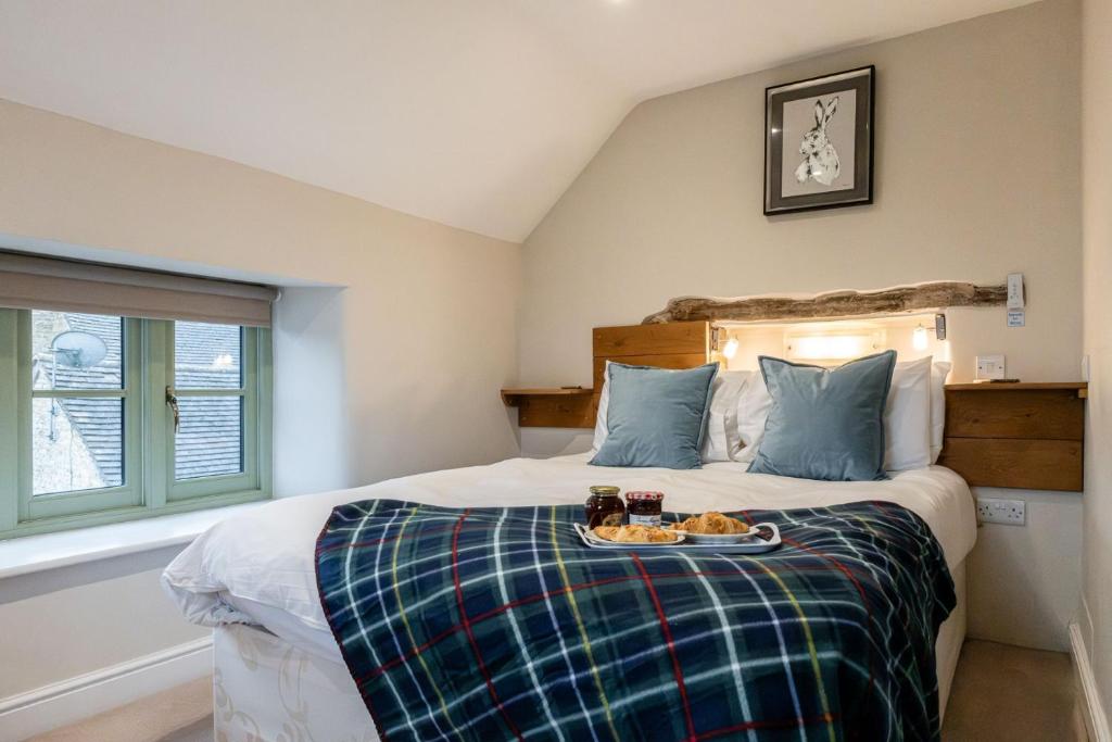 a bedroom with a bed with a tray of food on it at Evenlode Cottage in Stow on the Wold